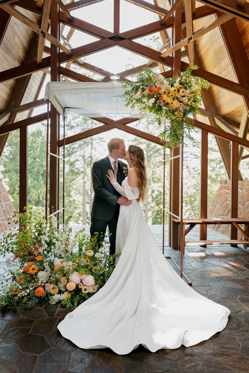 Couple kissing under the copper chuppah with full floral installation