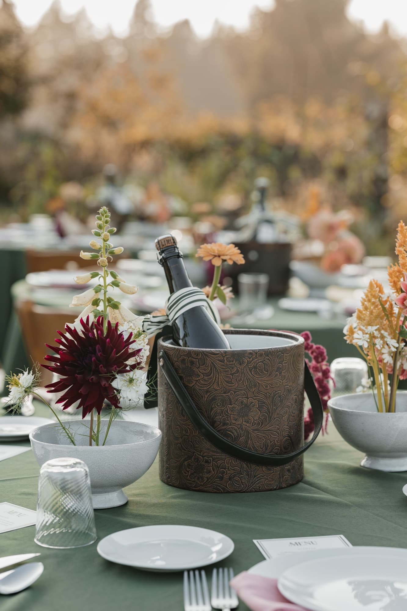 Tooled leather ice bucket styled with bud vases and green linens