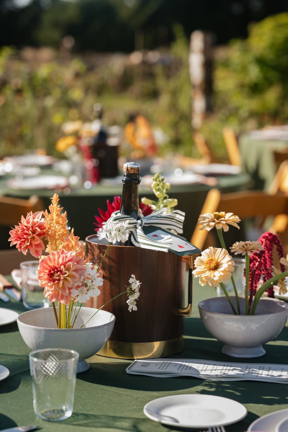 Wooden and brass ice bucket styled with dahlias on a reception table
