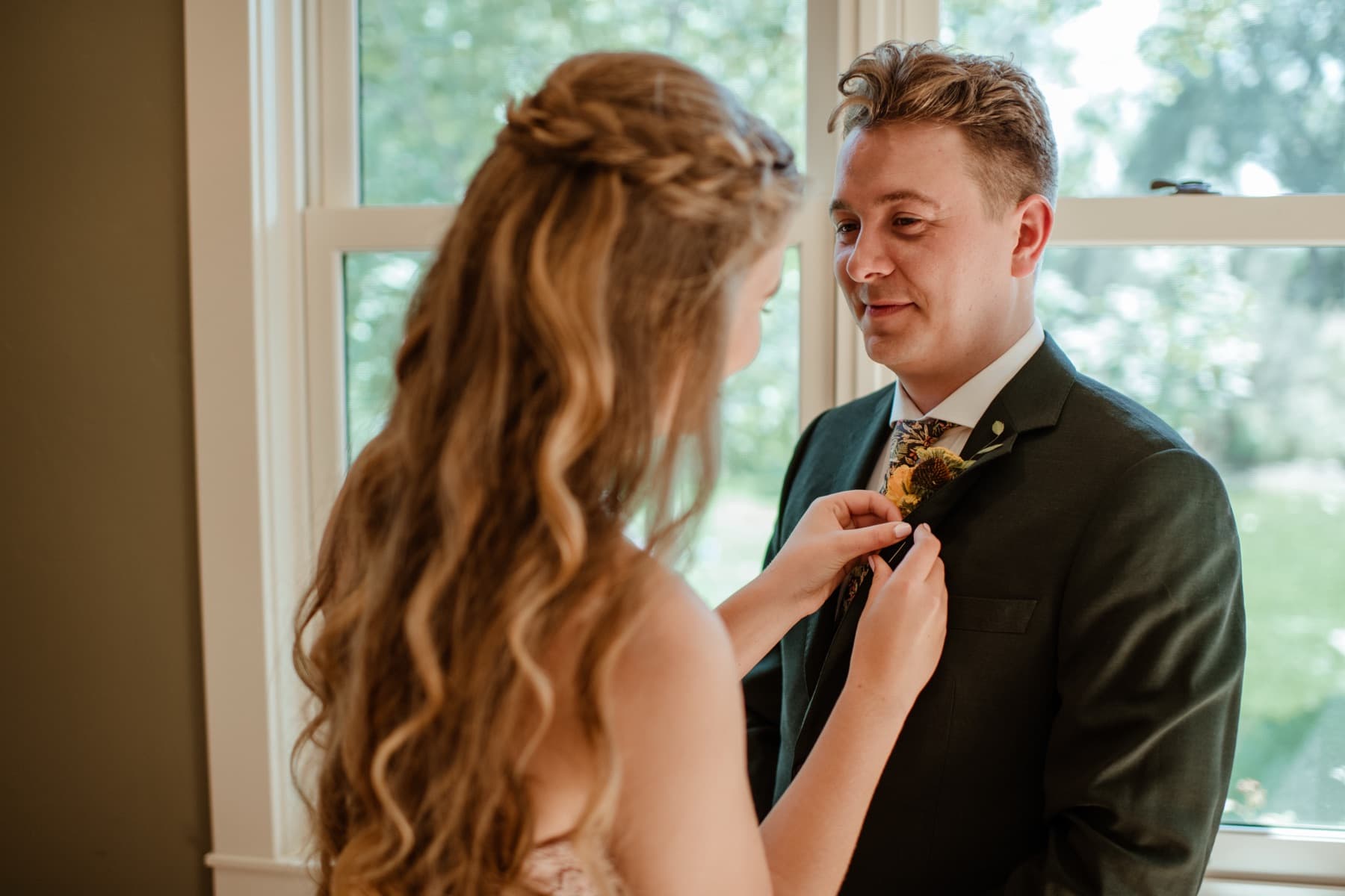 Bride pinning a boutonniere before the ceremony
